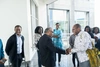 A group of people, with two men smiling and shaking hands.