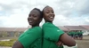 Two young women stood back to back smiling to camera 