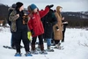 A group of people in snow gear and snow shoes in snowy terrain