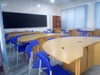 Modern curved wooden desks with bright blue chairs around them 