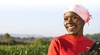 A woman smiling in front of green foliage.