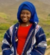 Aicha Tening Ndour wearing a blue and white cardigan with a red top, and a bright blue head wrap