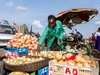Vegetable trader, Ciru, sorting through a basket of yellow onions at her outdoor stall, 4 x 3