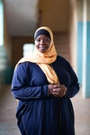 Hadija Hamisi wearing a smart dark blue outfit with a light orange headscarf