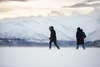 Tow young people snowshoeing wearing winter gear with snowy mountains in the background