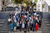 Large group of people gathers on outdoor steps facing to camera 