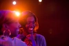 Two young women smiling, with a bright stage light behind them