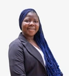 Freda Agyeman wearing a dark grey blazer with a white top and long styled blue braids