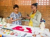 Iriza Ntako Hertigage LTD Company, two woman having a discussion at a vendors stall full of hand made jewelry and baskets
