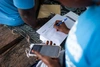 Two people in light blue t shirts recording some details of their work using a hand held digital device