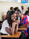  Girl seated at a school desk, laughing.