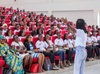 Image of a young woman speaking to an auditorium full of people