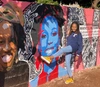Mantate Q. Mlotshwa standing beside the Inspiring Women Mural with herself featured.