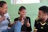 Two women and a man speaking in sign language and smiling at one another.