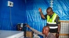 Vasco Hamisi working with one of his clients to connect a large freezer to solar electricity to assist with cooling for his beverage business in Kakuma refugee camp, 2025.