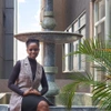 Joy Birungi sits next to a water fountain smiling to camera in smart clothing