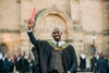 Student in graduation robes smiles to camera 