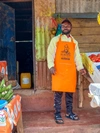 Erick Niyonzima at his grocery stall wearing an orange apron