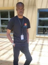 Salami Afizlai Omowumi standing in a black tshirt with a Mastercard Foundation logo and black slacks