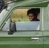 Annie Anuarithe, Tour Guide Driver, sat in a green vehicle smiling to camera