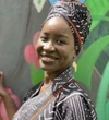Ndeye Khady Boye smiling and wearing a black and white patterned shirt with a similar pattern head wrap