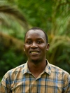 Esau Higenyi smiling in a beige and blue plaid shirt
