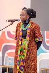 A young woman speaking at the Baobab Summit 2025 in a brightly coloured skirt and coat