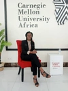 Woman sits on a red chair smiling to camera