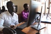 Samuel Munezero, right, is a member of CIYOTA. Along with other youth from Kyangwali, he is studying computers at the Windle Trust Centre in the settlement.