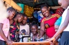 Christine Atenge, a participant in the Children’s Rights and Violence Prevention Fund’s vocational training program in Uganda with a group of people gathered around a sewing machine