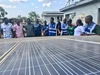 Vasco Hamisi co-founder of Okapi Green, wearing a blue vest and speaking to a group of people over a large solar panel