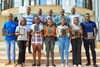 The thirteen Mastercard Foundation Scholars and winners of the 2023 Social Venture Challenge stood next to each other smiling holding their certificates