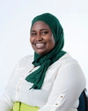 Jemila Abdulai wearing a white button up shirt, lime green trousers, and a dark green headscarf smiling