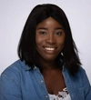 Adedoyin Adewunmi wearing a denim button up collared shirt and a white top
