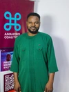 Agwu Kalu Ibe in a green tunic standing in front of an Amahoro Coalition poster