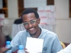 Associates Program in Senegal, a young man smiles while sitting with a group at a table