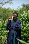 Selphine Akiru standing in a field wearing dark blue coveralls