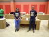 Two people stand smiling to camera with rabbits in the box behind them 