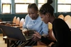 Two women looking at a laptop in a classroom.