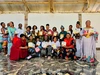 Esther Kitumaini in a group photo with 20 other individuals, each holding some of the baby porridge products.