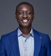 Tobi Aminu, Lead Lead for Programme Design & Planning smiling in a bright blue blazer with a light blue button up shirt underneath