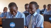 Two young girls sitting in a classroom on their laptop