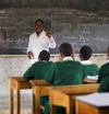 A teacher at the front of a classroom with students at their desks.