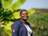 Naomi Eyanae smiling in dark blue branded coveralls, with a white t-shirt