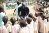 A group of young children crowded around a man smiling at them.