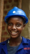 A young woman wearing a blue hard hat and overalls.