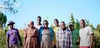 Esnath Divasoni stood with her family and other community members in Marondera, with a field in the background, smiling to camera 