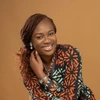 Adesola Sotande-Peters smiling to camera wearing a bright patterned top