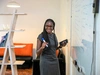 A young woman in professional wear standing and writing on a large whiteboard, Entrepreneur tour Kenya, 2017.