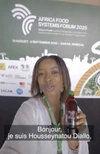 Housseynatou Diallo, Co-founder of Baaxu Maam Compagnie, a youth agripreneur participant at AFSF 2025, wearing a white tunic holding her products on display